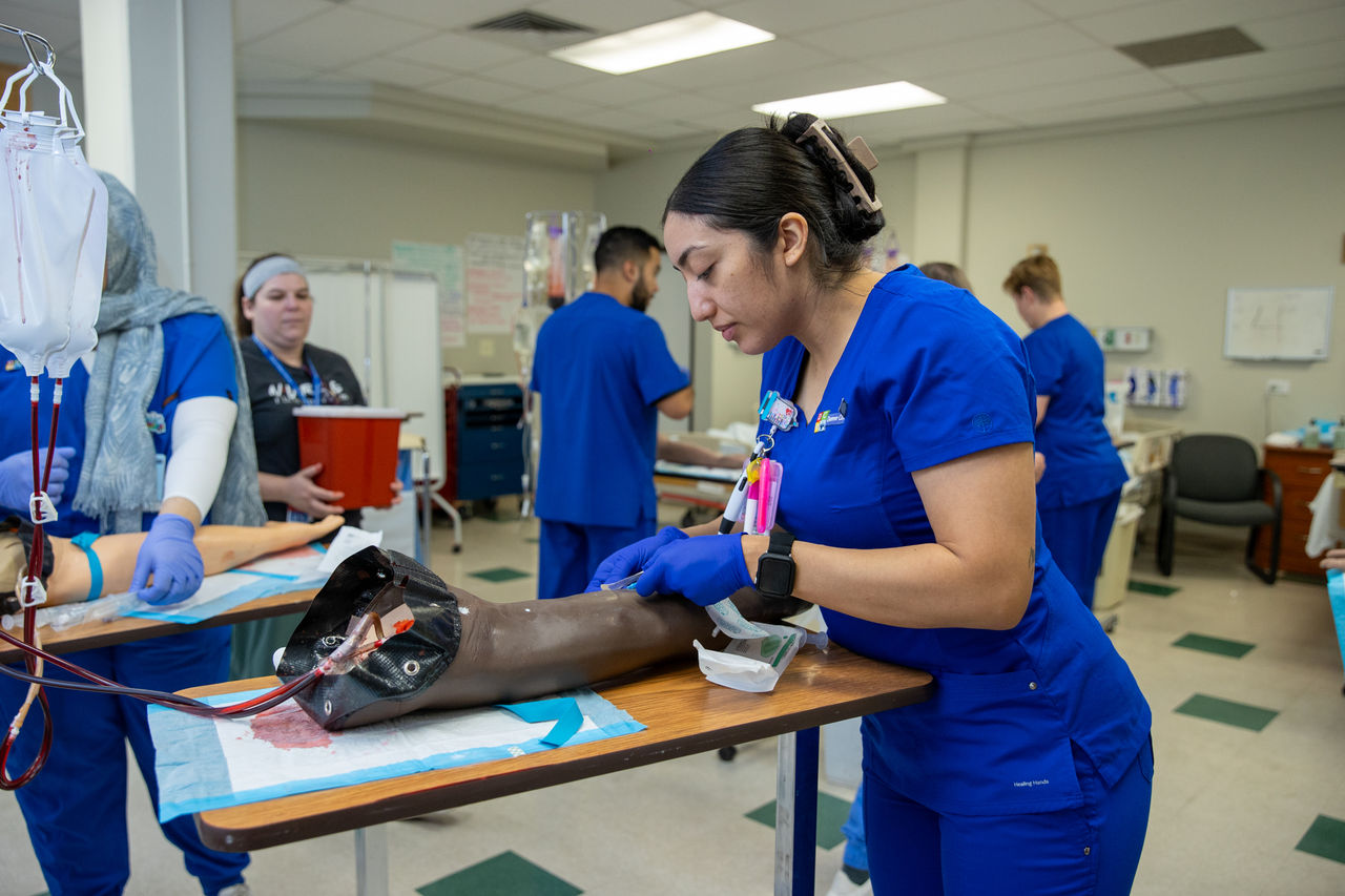 Nursing students practice IV insertion on training arm