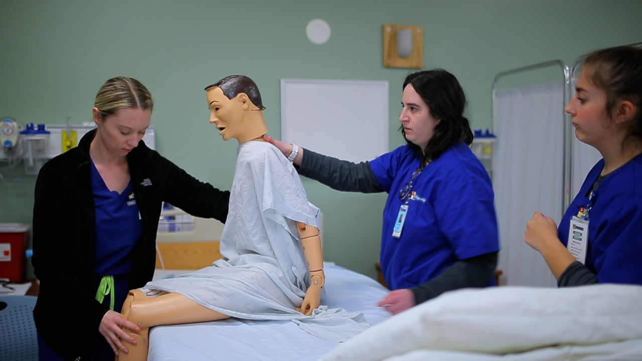 Medical students practicing patient care with training mannequin